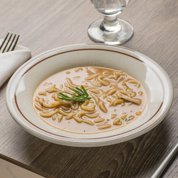 A Tuxton brown speckle rim soup bowl filled with soup on a table.