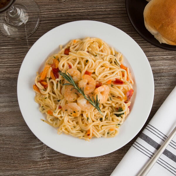 A Libbey medium rim porcelain plate with pasta, shrimp, and vegetables.