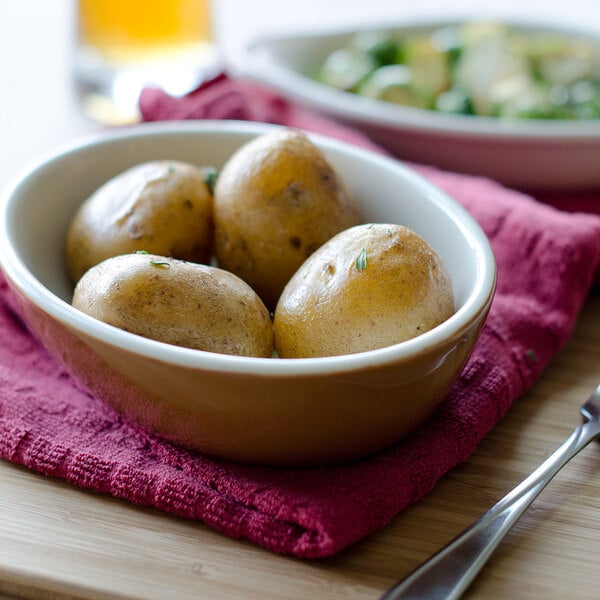 An Autumn/Eggshell Tuxton oval china bowl filled with potatoes.