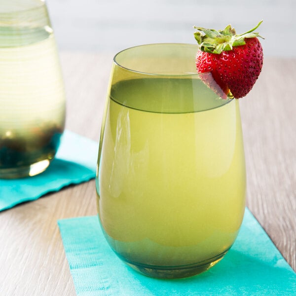 A Stolzle stemless wine glass filled with yellow liquid and a strawberry on the rim.