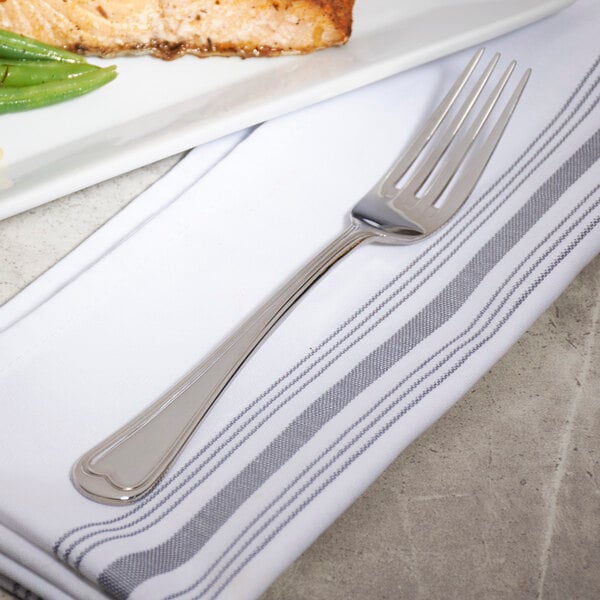 A Bon Chef stainless steel dinner fork on a white plate with food.