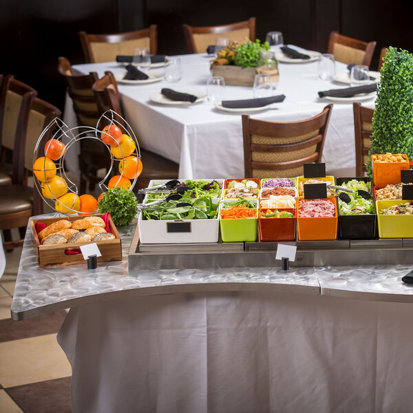 A Tablecraft translucent clear aluminum table cover on a table with food on it.