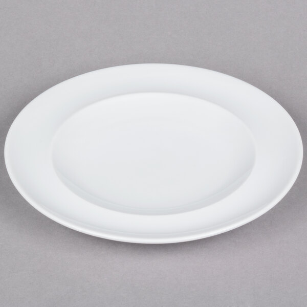 An Arcoroc white porcelain service plate with a rim on a gray surface.