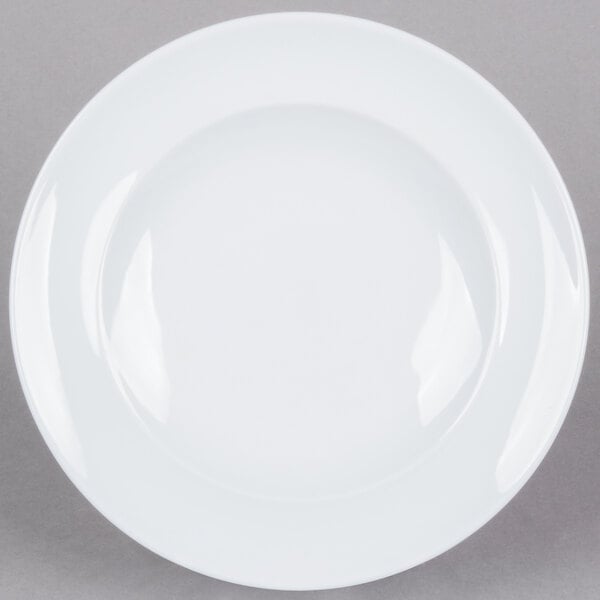 A close-up of an Arcoroc white porcelain service plate with a white rim.