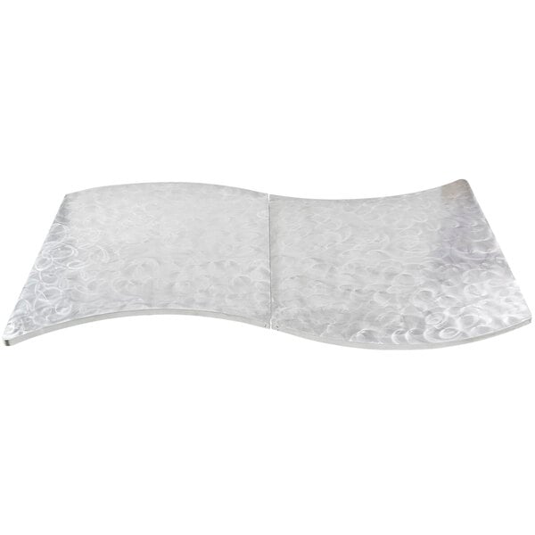 A Tablecraft aluminum table cover with a curved edge and a swirl pattern.