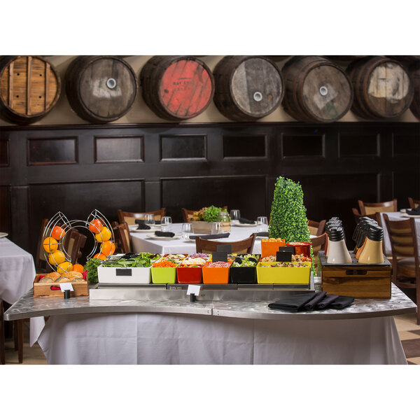 A Tablecraft translucent clear serpentine swirl aluminum table cover on a table with food.