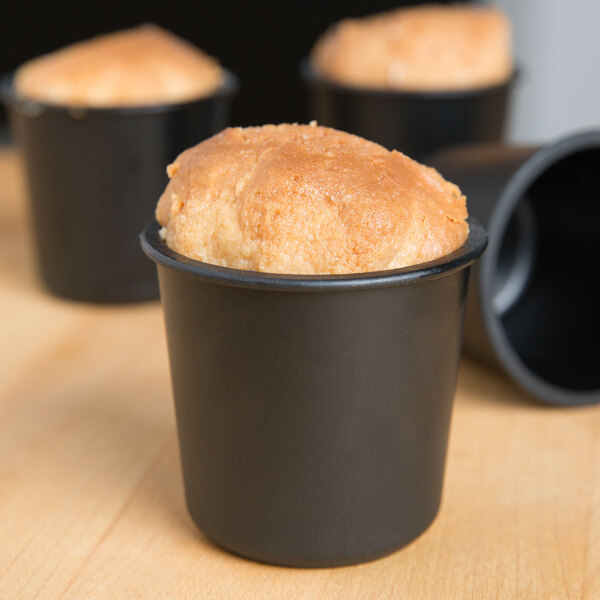 A close-up of a round brown Matfer Bourgeat rum baba or dariole mold filled with food.