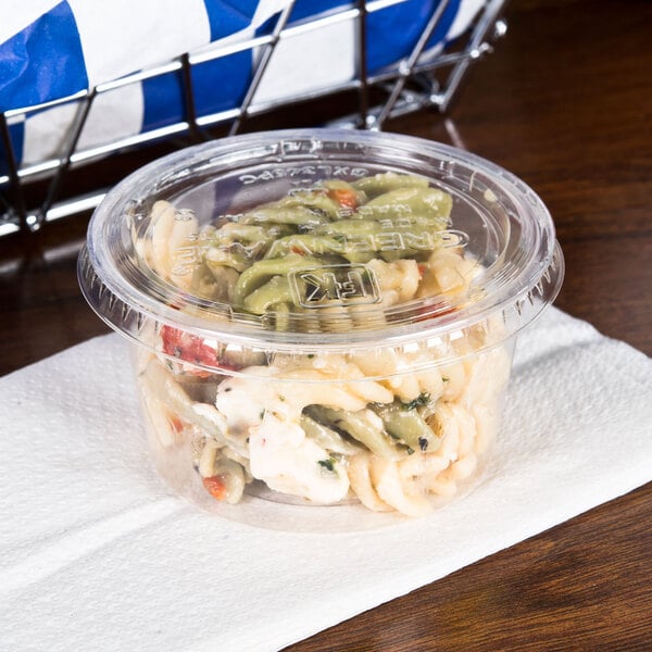A Fabri-Kal Greenware clear plastic lid on a plastic container of pasta.