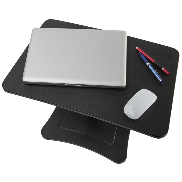 A Victor black wood stand-up laptop stand with a laptop and pen on a black table.