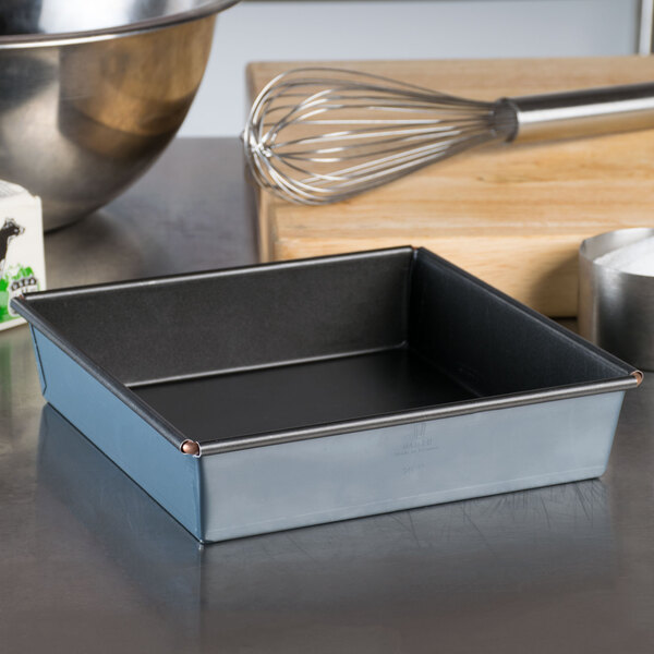 A Matfer Bourgeat square black metal cake pan on a table.