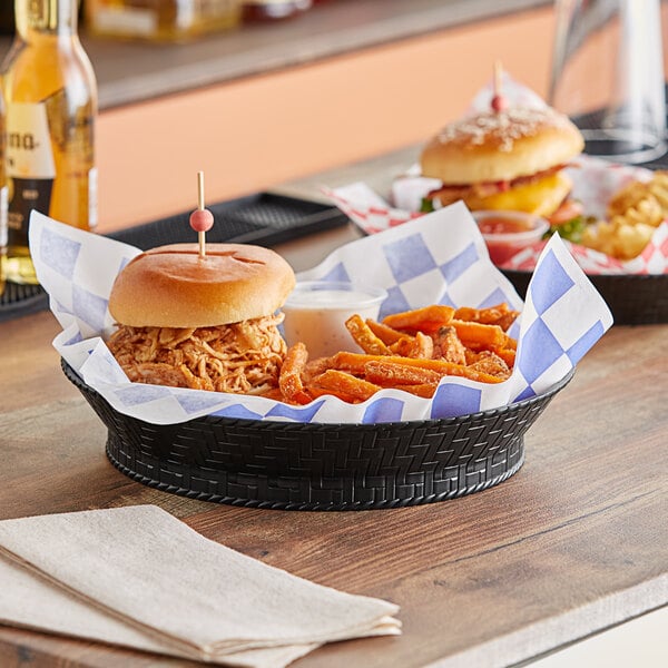 A black plastic fast food basket with a sandwich, fries, and a drink on a table.