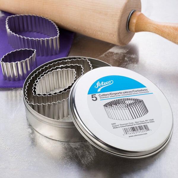 A metal tin with Ateco stainless steel football-shaped cookie cutters.