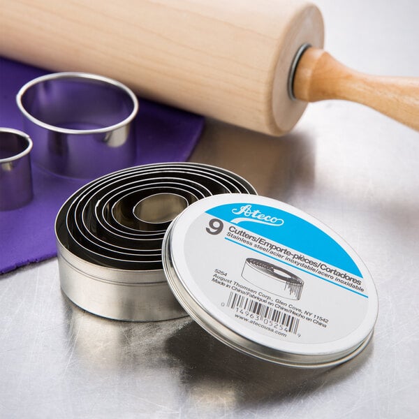 A rolling pin and Ateco oval cookie cutters on a counter in a professional kitchen.