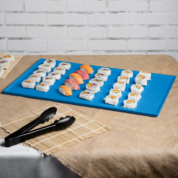 A Tablecraft sky blue cast aluminum rectangular cooling platter with sushi on a table.