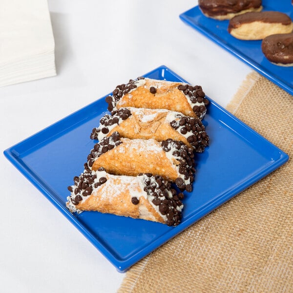 A Cobalt blue rectangular cast aluminum cooling platter with chocolate covered pastries on it.