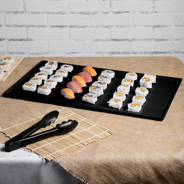 A Tablecraft black and green speckled cast aluminum rectangular cooling platter with sushi on a table.