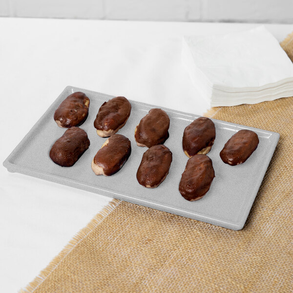 A Tablecraft natural cast aluminum rectangular cooling platter with chocolate covered donuts on a white surface.