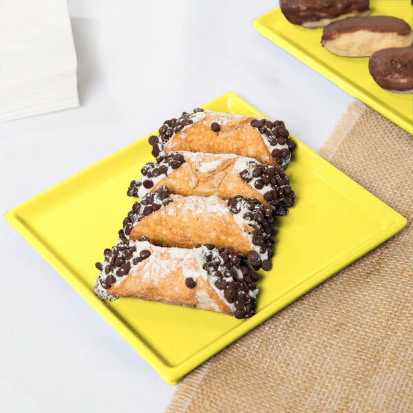 A Tablecraft yellow cast aluminum rectangular cooling platter with pastries on it.