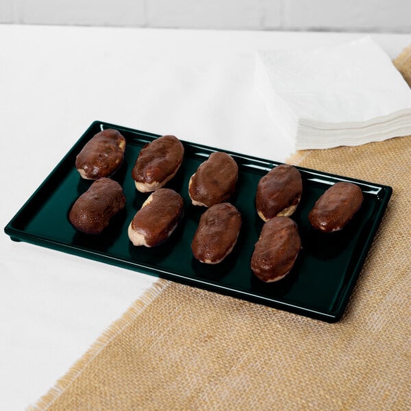 A Tablecraft hunter green cast aluminum rectangular cooling platter with chocolate covered donuts on it.