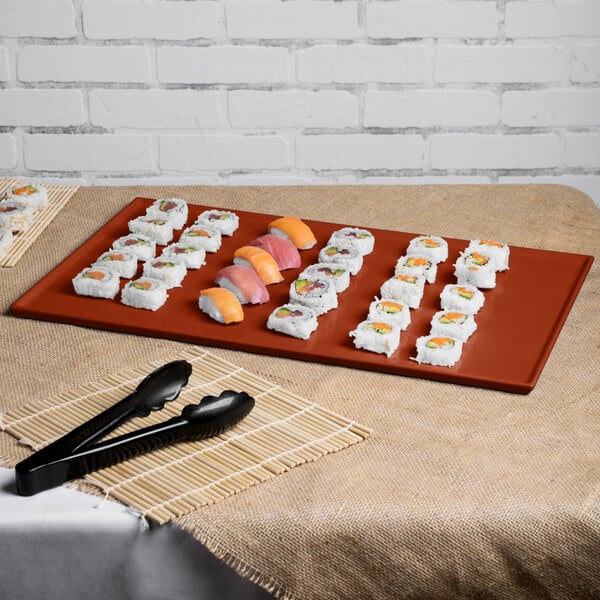 A Tablecraft copper cast aluminum rectangular cooling platter holding sushi on a table.