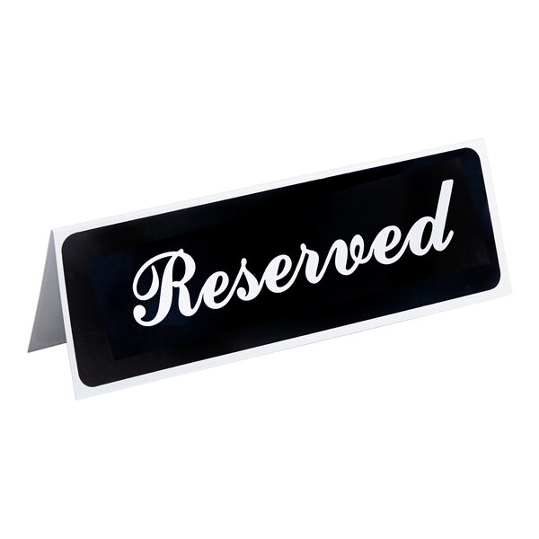A black and white tent-style sign with the word 'Reserved' written in cursive.