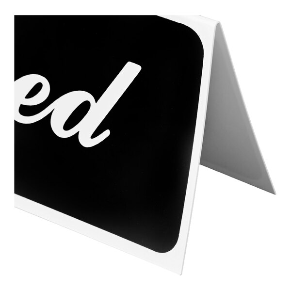 A partial view of a black and white tent-style sign with the word 'ed' in white script, likely part of the word 'Reserved.'