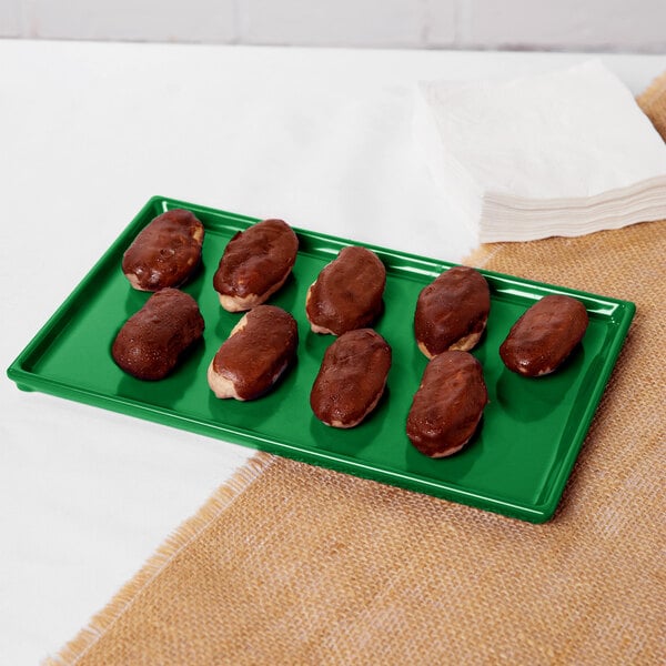 A green Tablecraft rectangular tray with chocolate covered donuts on it.