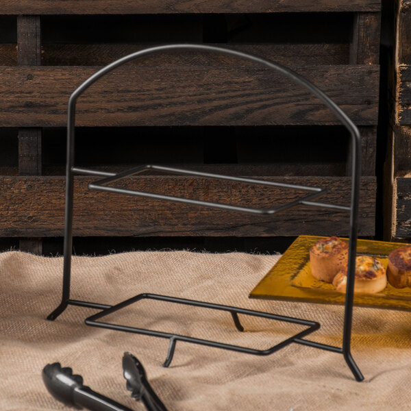 A black metal Clipper Mill 2 tier table riser with food on plates.