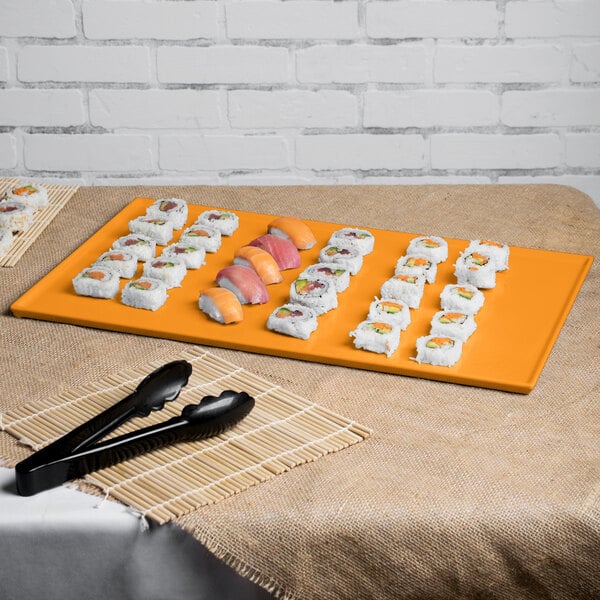 An orange Tablecraft rectangular cast aluminum cooling platter with sushi on it.