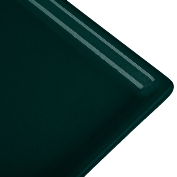 A close-up of a dark green Tablecraft cast aluminum rectangular cooling platter.