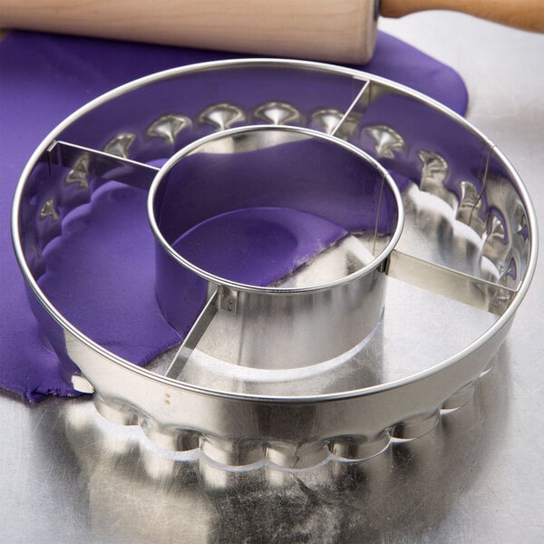 A stainless steel Ateco jumbo frill cutter on a table with a rolling pin.