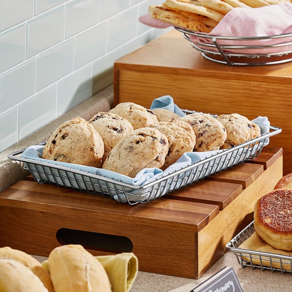 A Clipper Mill stainless steel rectangular grid basket holding a tray of cookies on a bakery counter.