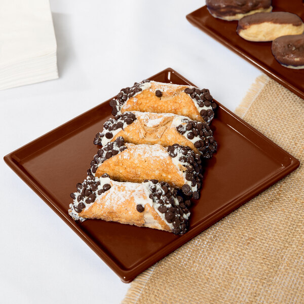 A Tablecraft brown cast aluminum rectangular cooling platter with chocolate covered pastries on a table.