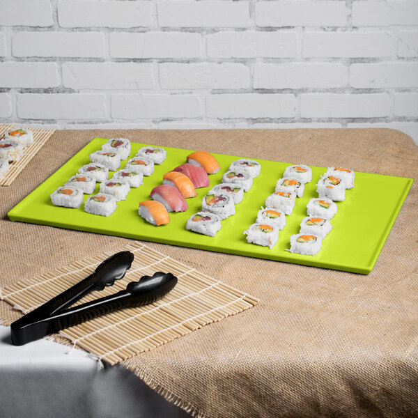 A Tablecraft lime green cast aluminum rectangular cooling platter on a table with sushi and tongs.