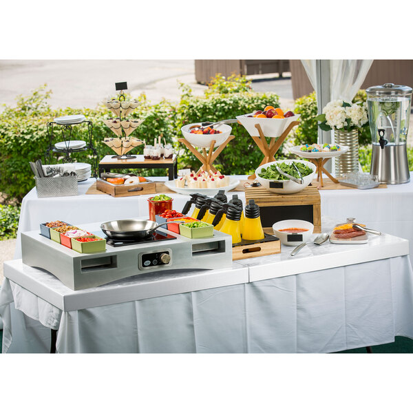 A Tablecraft translucent clear metal table cover on a table with food and drinks on it.