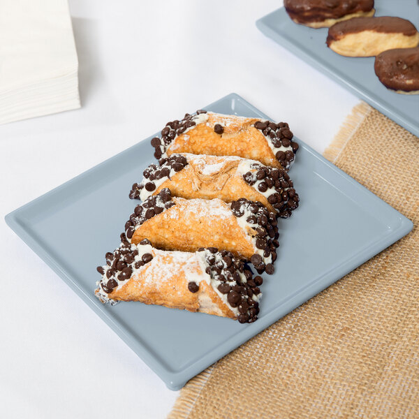 A Tablecraft gray cast aluminum rectangular cooling platter holding pastries with chocolate and nuts.