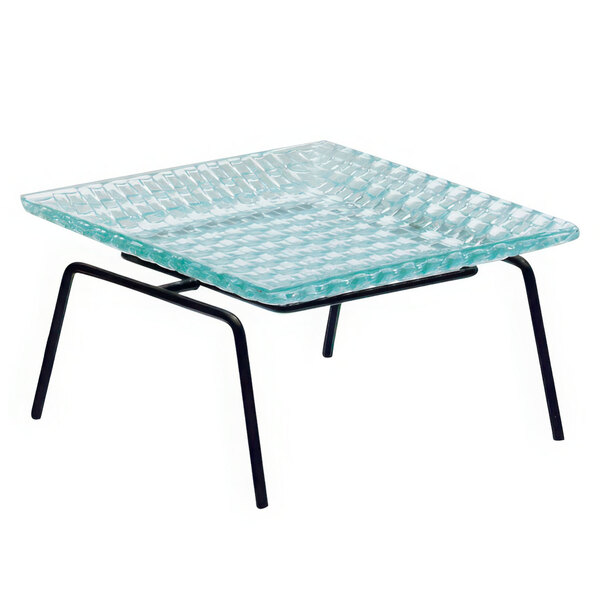 A black powder coated iron display riser holding a clear square plate on a table with black legs.