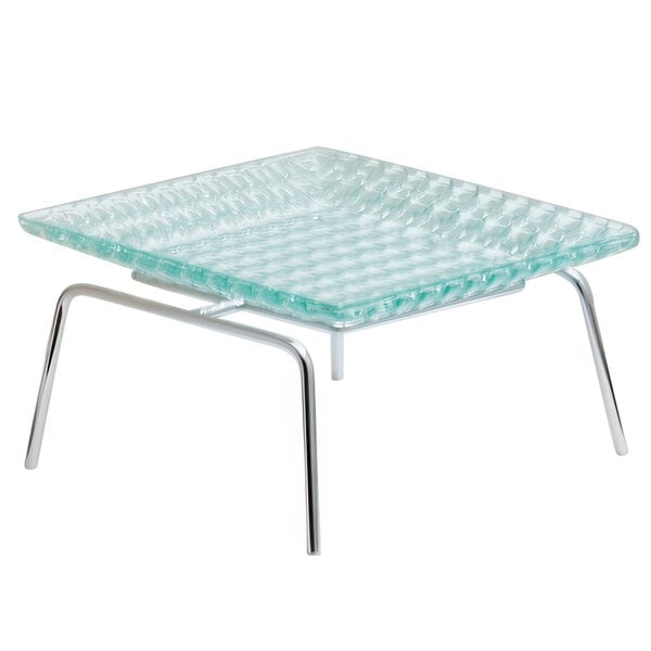 A Clipper Mill chrome-plated iron riser on a glass square table with metal legs.