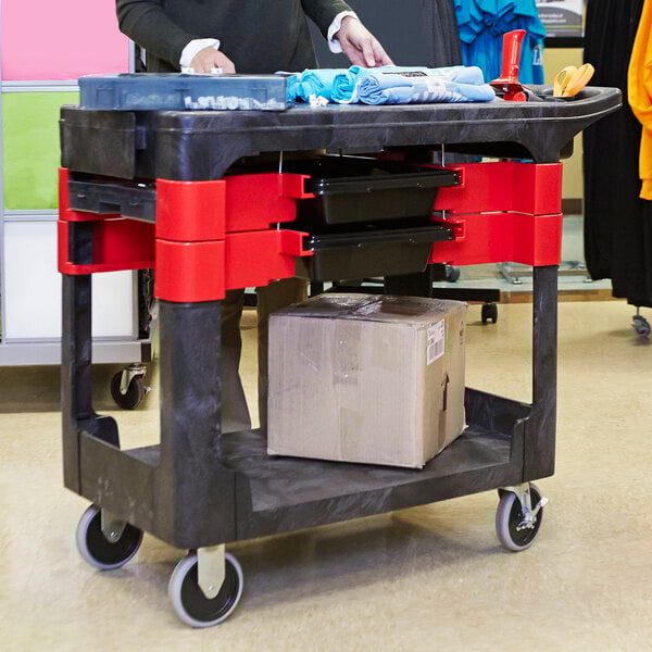 A Rubbermaid black TradeMaster cart with parts bins and boxes on it.