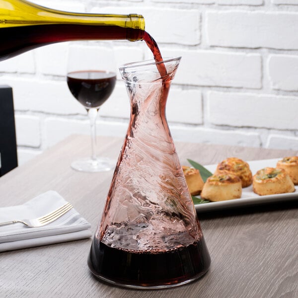 A Stolzle Pisa carafe being filled with red wine from a glass.