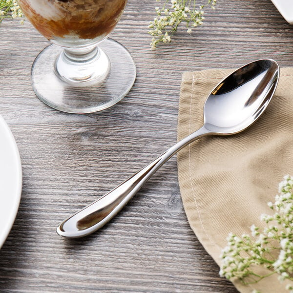 A Reed & Barton Holliston stainless steel dessert spoon on a napkin next to a glass of ice cream.