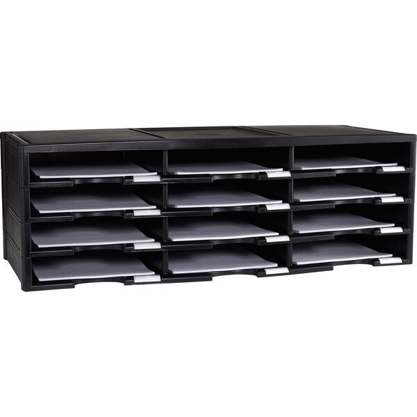 A black Storex plastic literature organizer with twelve compartments on a table with white paper in some sections.