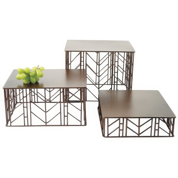 A metal Clipper Mill rectangular riser set on a table with green grapes.