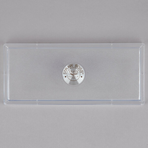A rectangular clear plastic lid with a silver button and a logo on it.