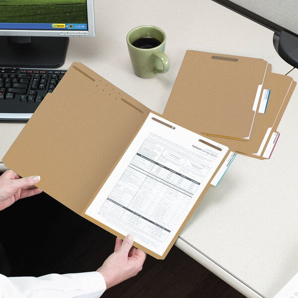 A person holding a Smead letter size file folder with papers.