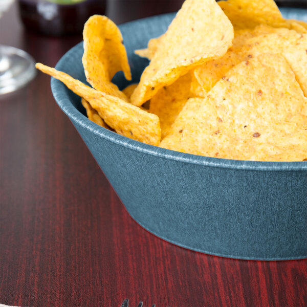 A blue polyethylene round basket filled with blueberries on a table.