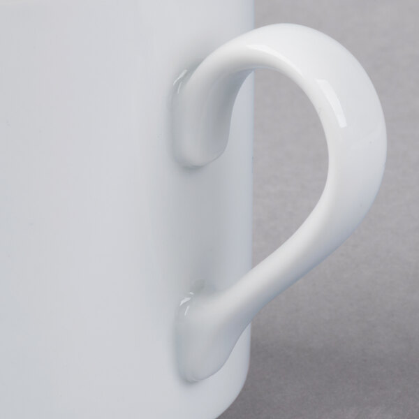 A close-up of a Schonwald white porcelain mug with a handle.