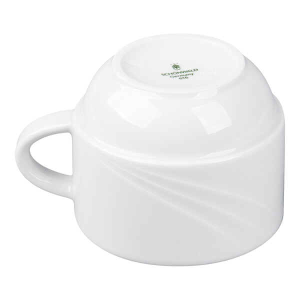A white porcelain cup is shown upside down with a handle on the left side and subtle swirl patterns on its surface.