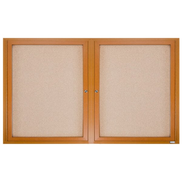 A close-up of an Aarco enclosed bulletin board with a natural oak frame.