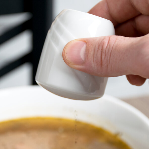 A person holding a Schonwald Donna white pepper shaker.